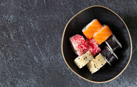 Sushi rolls on black plate on dark background with copy space on the leftの写真素材