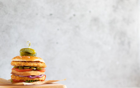 Chicken burger on wooden board on light background with copy space on the rightの写真素材