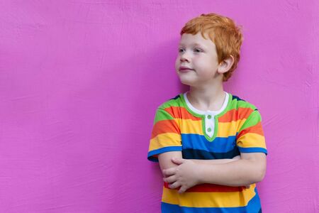 Fashionable little boy. Red-haired handsome kid model wearing trendy striped casual shirt posing...