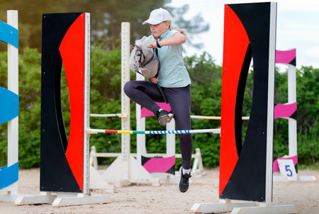 Saint-Petersburg, Russia, June 12 2022. Exhibition Hipposphere. Competitions in hobby. Girl jumping on hobby horse. Equestrian sport. Jumping competition. Champion. Horse sportのeditorial素材