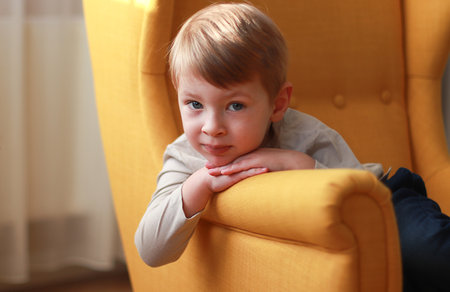 Little blond boy on the yellow armchair. International Childrens Day.の写真素材