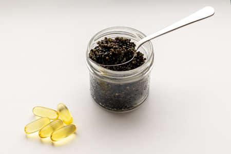 Black caviar and a vitamins capsules on a white background with a copy space.の写真素材
