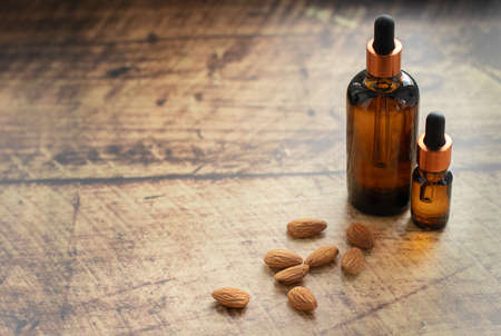 Brown glass bottles with almond oil an almond nuts on wooden background. Beauty and spa salon, cosmetics concept.の写真素材