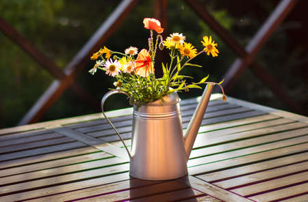 A bouquet of red poppies and daisies in a metal watering can. Summer floral background. Copy spaceの写真素材