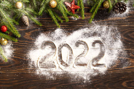 Christmas background. Fir branches with Christmas decorations on a wooden background and numbers on...