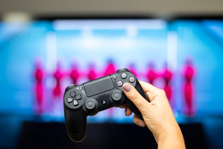Moscow, Russia - October, 19, 2021. Hand in the foreground with Playstation joystick and the screensaver of Squid Gameのeditorial素材