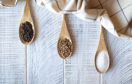 Seasonings salt, pepper and coriander in wooden spoons on a gray background.の写真素材