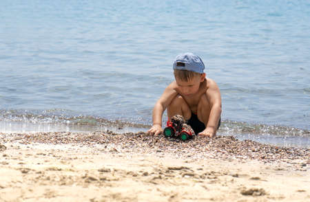 Little boy playing with toys on the seaside. Holidays in Greece. Happy childhood conceptの写真素材