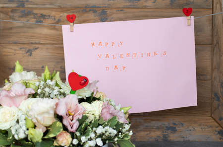 Printed inscription Happy Valentine's Day on a piece of paper hanging from a rope on clothespins.の写真素材