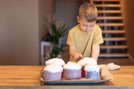 Little funny boy bakes and tastes Easter cake.の写真素材