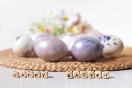 Easter concept. Purple eggs on a straw cloth and wooden letters happy Easter.の写真素材