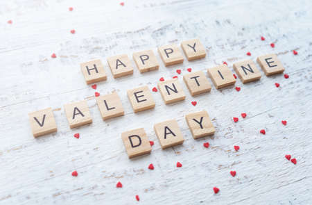 happy st. Valentine's day greetings card. Wooden letters on the white background with small scattered red hearts.の写真素材