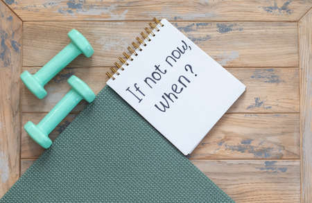Dumbbells, exercise mat and notepad with motivational inscription - if not now, when. Sports, discipline and planning conceptの写真素材