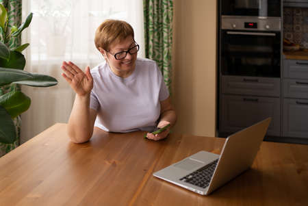 An elderly woman works at a laptop and communicates via video call. Modern technologies and aged...