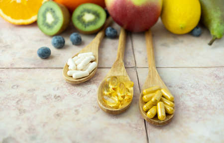 Natural fruits and multivitamin capsules. natural and synthetic sources of vitamins.の写真素材