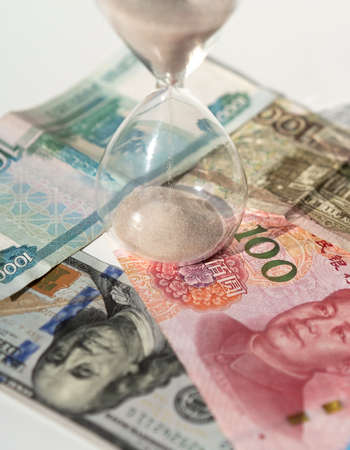 Rubles, dollars, yuans and hourglass on the white background. Time is money concept. global...