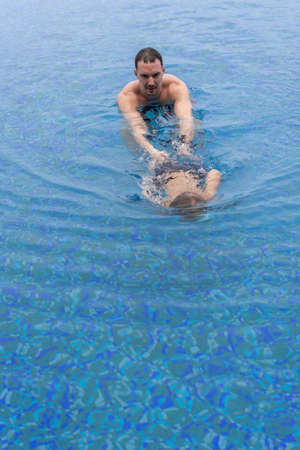Dad and son are playing in the swimming pool. Father teaches son to dive.の写真素材