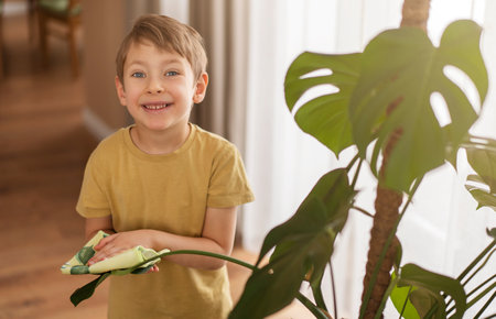 A little boy helps with cleaning around the house and taking care of the plants. Spring cleaning concept.の写真素材