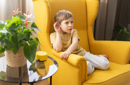 A little boy sits in a chair and communicates with a smart speakerの写真素材