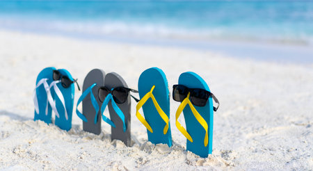 Three pairs of flip flops in sunglasses on the beach on the background of the ocean in the Maldives. Family beach holiday concept.の写真素材