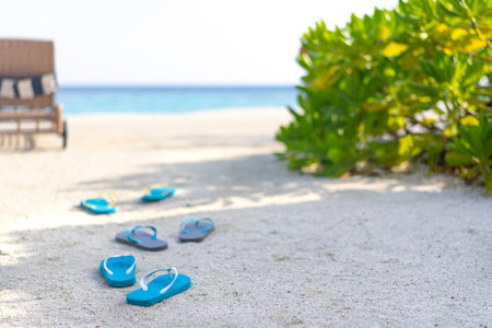 Three pairs of flip flops on the beach on the background of the ocean in the Maldives. Family beach holiday concept.の写真素材