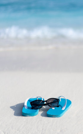 Flip flops and sun glasses on the beach on the background of the ocean in the Maldives. Beach holiday concept.の写真素材