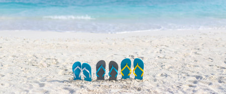 Three pairs of flip flops on the beach on the background of the ocean in the Maldives. Family beach holiday concept. Bannerの写真素材