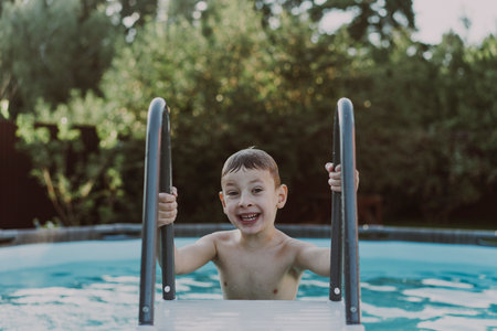 Little boy swims in the pool at their summer cottage. Back yard vacations concept