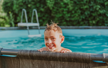 Little boy swims in the pool at their summer cottage. Back yard vacations concept