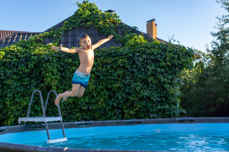 Little boy swims in the pool at their summer cottage. Back yard vacations concept.の写真素材