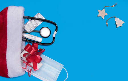 Medical Christmas banner with pills, gift present box and Santa hat on blue background. Medicine new...
