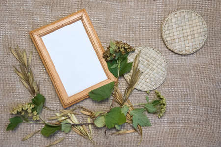 Top view flat lay autumn composition. Blank yellow frame, plants, seeds and straw on sackcloth...