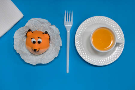 Edible cake fox and cup orange juice on blue background, top view, flatlay. Cute animal food art...