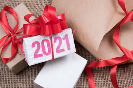 2021 figures on Christmas gift box. Wrapping boxes in brown paper. Hand made craft gift boxes of paper at New Year holiday. Top view.の写真素材
