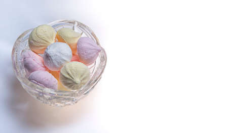 Small homemade meringue kisses. Banner with meringue cookies in glass bowl isolated on white backgroundの写真素材