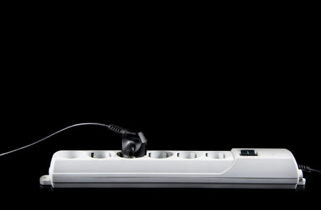 Closeup of electrician plugging extension cords isolated on black background.