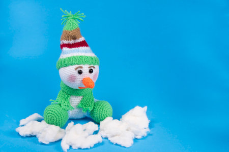 Toy knitted snowman in cap and scarf on blueの写真素材
