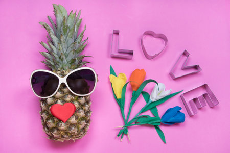 Pineapple with sunglasses, message love, tulip flowers on pink background. Happy women's day conceptの写真素材