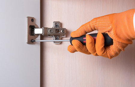 Woman repairing furniture hinge close up. Do it yourself concept. Women home service concept. Close...