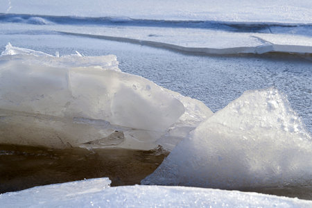 Spring thawed ice on lake. Background texture. Frozen ice and snow by river side.