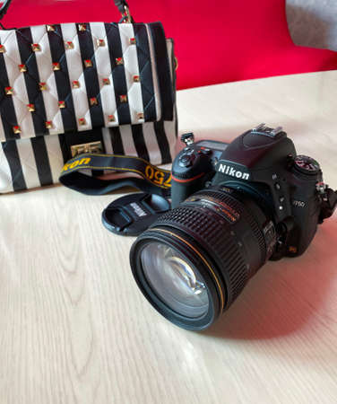 Perm, RUSSIA, June 2020. Photo camera Nikon D750 and striped bag on table in room