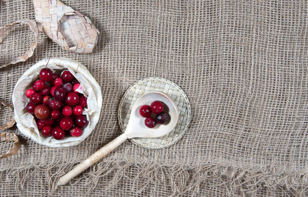 Cranberries in wicker basket on burlap background, bast shoe and wooden spoon. Copy spaceの写真素材