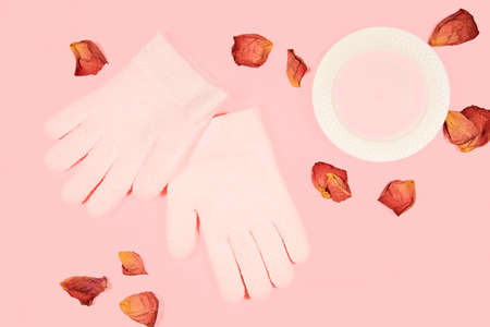 Spa gel moisturizing gloves and rose petal isolated on pink background. Skin care concept.