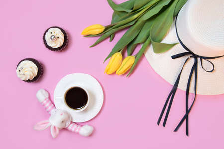 Easter bunny rabbit, coffee cup, white women's hat and spring tulip flowers on pink background. Flat...