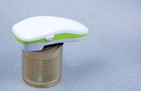 Electric can opener and canned good isolated on gray background