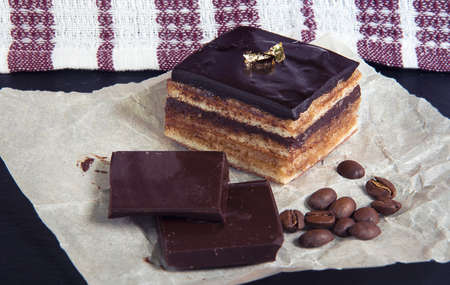 Chocolate cake named âParis Operaâ and white coffee cup. Classic french "Opera" cake. Home cooking. Fabric background.の写真素材