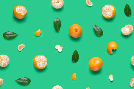 Tangerine orange seamless pattern. Isolated mandarin pieces on green background. Flat lay of whole and half tangerines, peeled mandarins and leaves.の写真素材