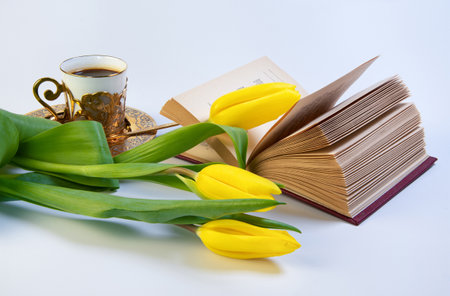 Yellow tulip flowers, book, golden coffee cup isolated on white background. Copy space for text.