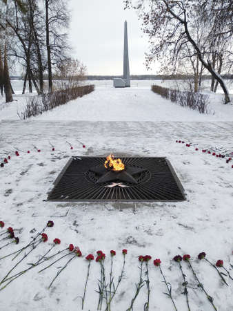 Monument with eternal flame red flowers. Burning fire and star - symbol of memory about Second World War.の写真素材