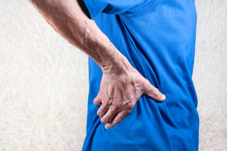 hand holding lower back, elderly man suffering from pain in side. White backgroundの写真素材